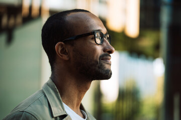 A young unshaven afro american smiling man wearing eyeglasses on the street. Outdoor portrait.