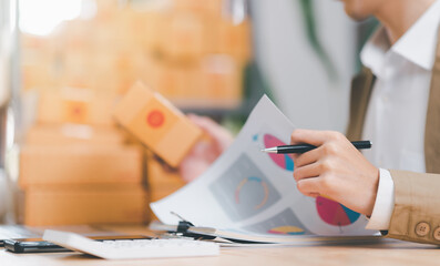 Fototapeta premium Startup or small business entrepreneur,check business growth report,order management in online stores, shopping on the internet,Selling online on the Internet,SME,shipping boxes,e-commerce