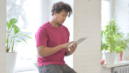 African Man Using Tablet while Sitting in Window