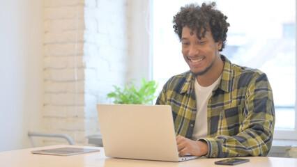 African Man Cheering Results on Laptop in Office