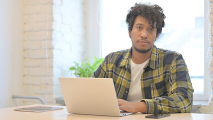 African Man Looking at Camera while using Laptop
