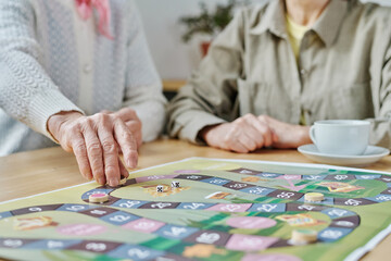 Close-up of senior woman making a move on the map, she playing board game with her friend at table