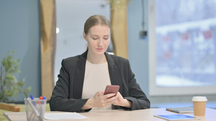 Businesswoman Browsing Internet on Smartphone in Office