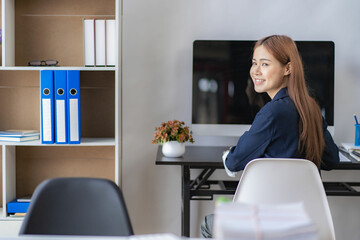 Asian woman using desktop computer for doing financial mathematics on desk, tax, reporting, accounting, statistics and analytical research concept, side view.