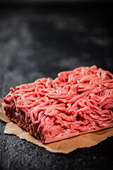 Raw minced meat on paper on the table. 