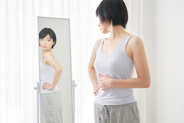 鏡で体型をチェックする女性