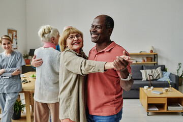 Happy senior couple learning to dance during lesson in nursing home