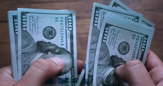 Close up male hands counting US Dollar bills or paying in cash. Male hands counting stack of hundred-dollar US banknotes. Businessman is counting cash. the concept of investment, money exchange