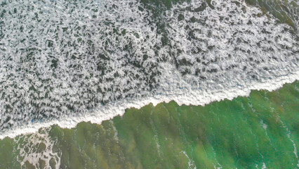 Aerial view of gentle waves along the beautiful shoreline