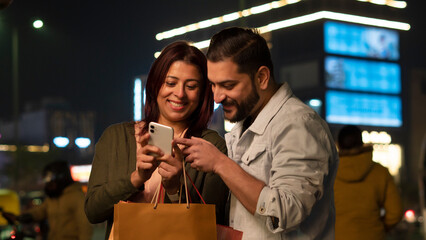 Happy young couple with shopping bags at night