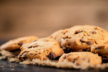 Pile of homemade cookies with pieces of milk chocolate on the table.