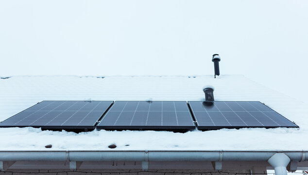 panel at rooftop with snow. removing snow off solar panels in winter. Removing snow photovoltaic system - solar cells. snow covers panels - no producing power. energy efficiency 