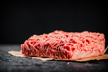 Raw minced meat on paper on the table. 