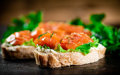 Sandwich with pieces of salmon and greens. 