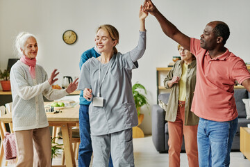 Senior people having dance lesson in nursing home, they dancing with their caregiver