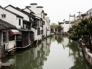 Fototapeta na wymiar Water canal in Suzhou old town lined with white walled houses