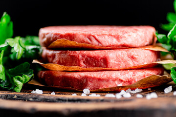 Raw burger on a wooden cutting board with parsley. 