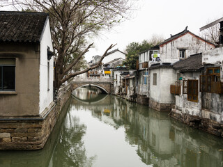 Fototapeta na wymiar Water canal in Suzhou old town lined with white walled houses