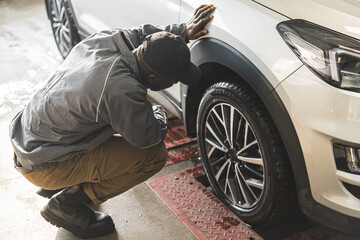 Mechanic checking geometry and suspension of a car wheel using precision tools. High-quality photo. - obrazy, fototapety, plakaty