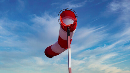 Windsack mit Mast vor leicht bewölktem Himmel