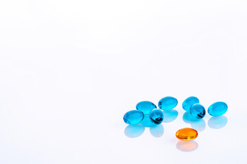 Orange jelly pill with blue jelly pills placed on white background.