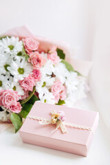 Obraz na płótnie Canvas Beautiful bouquet of rose and chrysanthemums flowers and pink gift box on white table background. Gift for holiday, birthday, Wedding, Mother's Day, Valentine's day, Women's Day. Floral arrangement.
