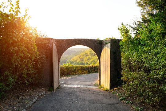 Arch door on the old fence wall is open that to see view of mountain and sunlight background on the morning day. - Powered by Adobe
