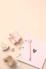 Valentines Day flat lay composition. Photo album, gift box, heart-shaped coffee cup, candles on pastel beige background. Flatlay, top view.