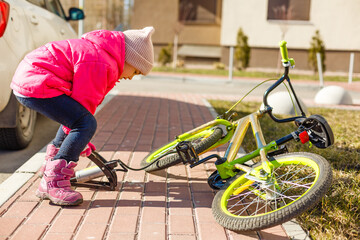 Naklejka premium a little girl pumps up a bicycle tire.