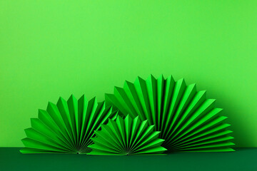 Happy St Patrick's Day celebration concept. Patricks Day paper fans ornaments on green background. Abstract, minimal style.