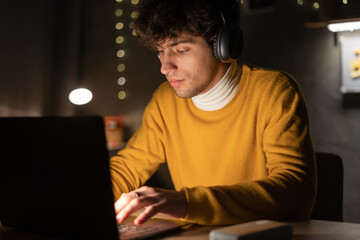 Young arabic ethnic businessman or student remote working overtime, learning online late at night at home or in dark dormitory room using laptop computer at workplace.