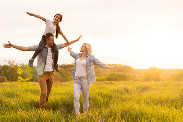 Happy family: mother father and child daughter on nature on sunset