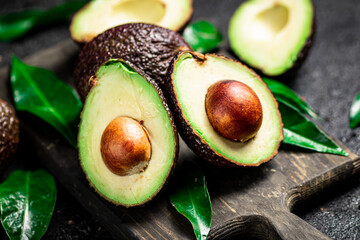 Fresh avocado with foliage on a cutting board.