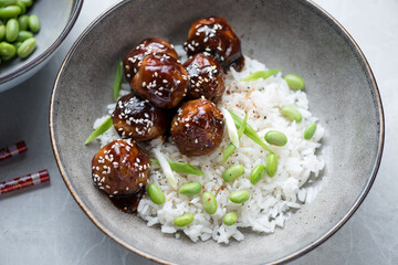 White rice and meatballs in teriyaki sauce served in a grey plate, middle close-up, horizontal shot
