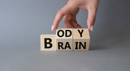 Body vs Brain symbol. Businessman hand turns wooden cubes and changes word Brain to Body. Beautiful grey background. Business and Body vs Brain concept. Copy space.
