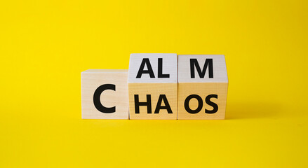 Calm vs chaos symbol. Turned wooden cubes with words Chaos and Calm. Beautiful yellow background....