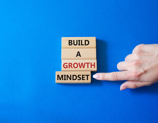 Build a growth mindset symbol. Concept words Build a growth mindset on wooden blocks. Businessman hand. Beautiful blue background. Business and Build a growth mindset world concept. Copy space.
