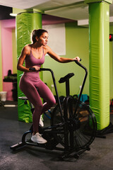 Fototapeta na wymiar Young woman is doing a warm-up on a bicycle in the gym