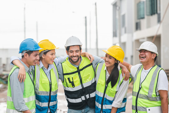 Group of happy construction team with architect engineer laughing together at building site