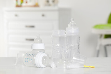 Clean baby bottles with nipples after sterilization and cleaning brush on white table indoors