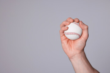Man with baseball ball on light grey background, closeup. Space for text