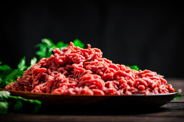 Minced meat on a plate on the table with parsley. 