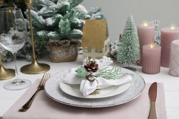 Festive place setting with beautiful dishware, cutlery and cone for Christmas dinner on white wooden table