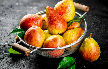 Fresh pears with leaves in a colander. 