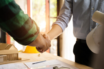 Construction workers, architects and engineers shake hands while working for teamwork and cooperation after completing an agreement in an office facility, successful cooperation concept.
