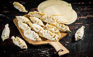 Raw dumplings gyoza on a wooden cutting board. 