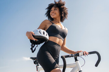 A young curly-haired woman contented with the activity of a bicycle riding in a tracksuit.