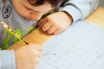 child writing with a pencil on the copybook, elementary school, education
