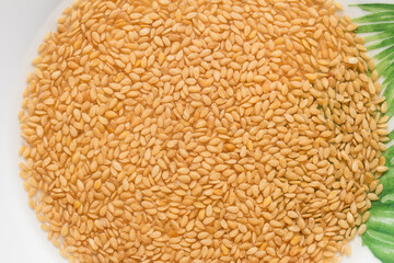 The top view of a close-up of Soaked flax seeds forms a circle on a ceramic plate with green leaves painted on the rim. Healthy food.