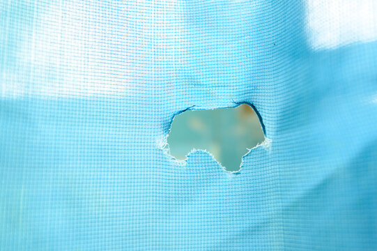 A hole in the shape of Ukraine on a blue piece of cloth or part of the flag of Ukraine.